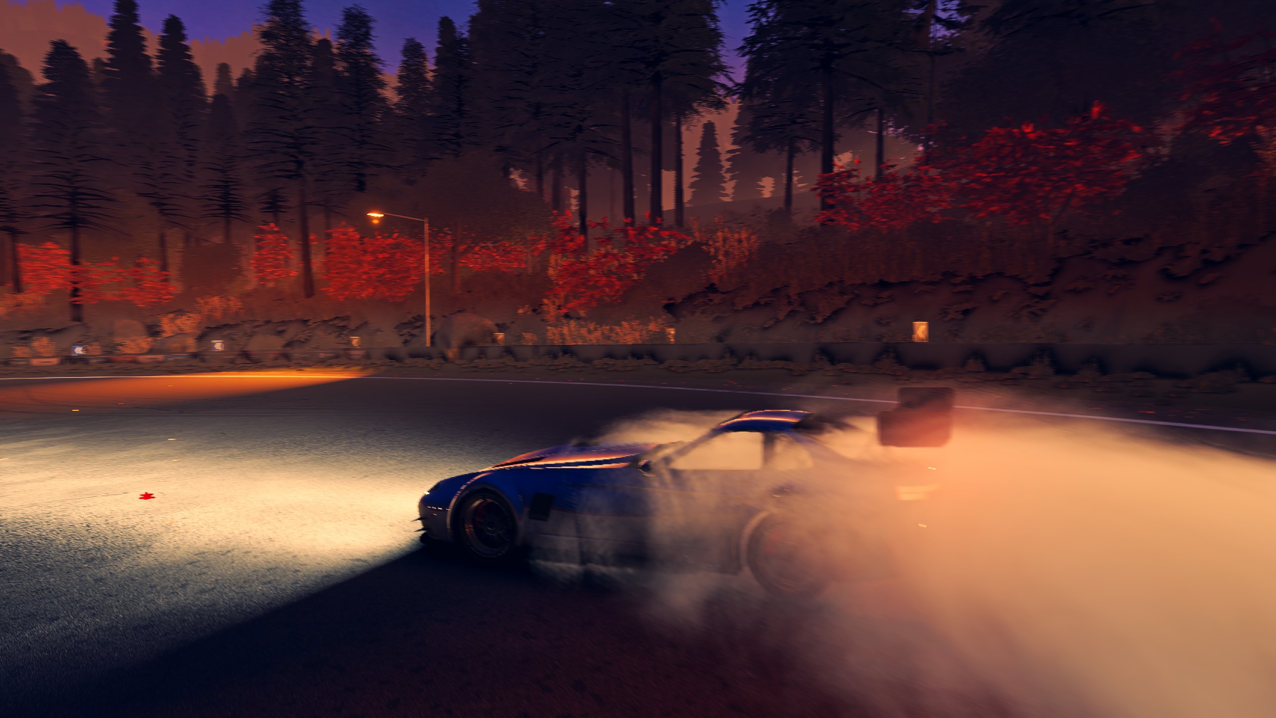 The car drifting on a mountain road at night, headlights cutting through tyre smoke